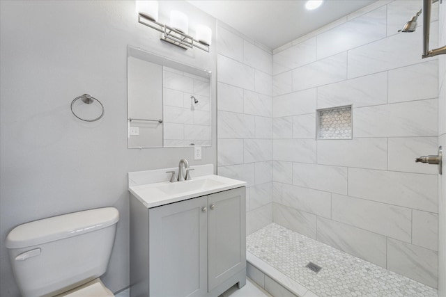 bathroom with vanity, toilet, and a tile shower