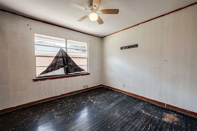 unfurnished room with ceiling fan, ornamental molding, and wood walls