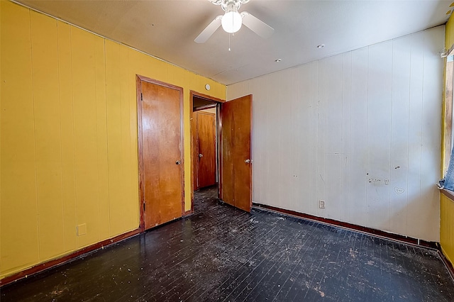 empty room featuring ceiling fan and wooden walls