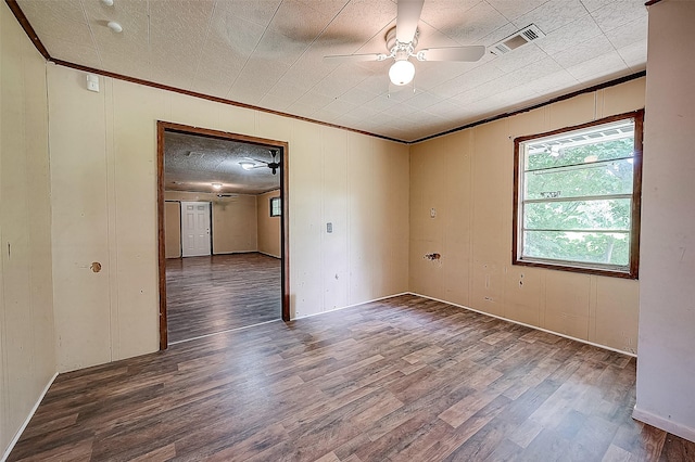 empty room with hardwood / wood-style floors, wooden walls, ceiling fan, and crown molding