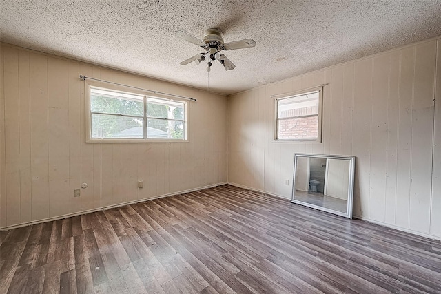 unfurnished room with ceiling fan, dark wood-type flooring, and wood walls