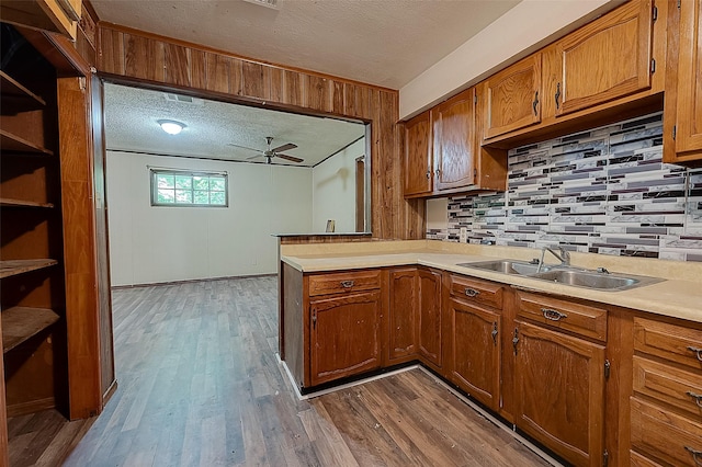 kitchen featuring ceiling fan, sink, wood-type flooring, a textured ceiling, and decorative backsplash