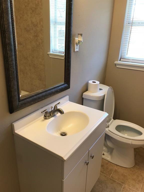 bathroom featuring toilet, vanity, tile patterned floors, and plenty of natural light