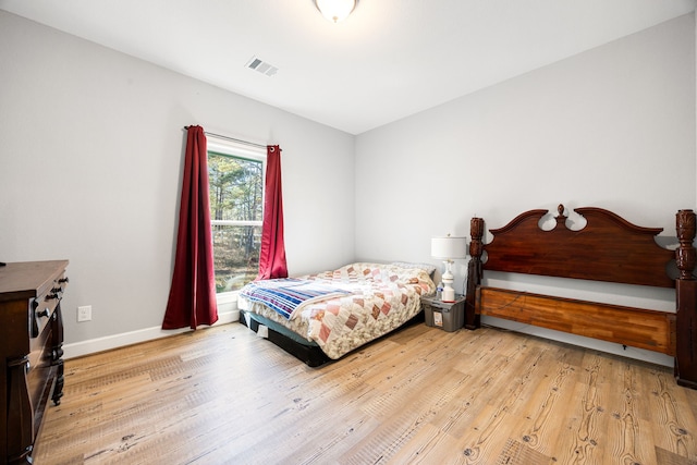 bedroom featuring visible vents, baseboards, and wood finished floors