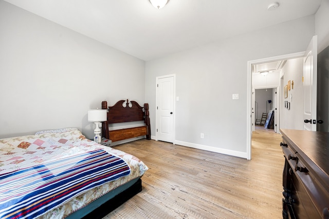 bedroom with baseboards, light wood-style floors, and attic access