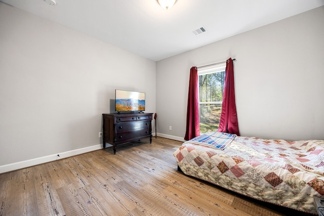 bedroom with visible vents, baseboards, and wood finished floors