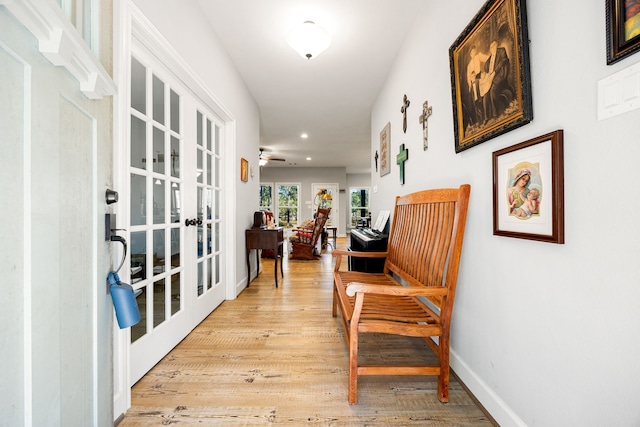 hall featuring light wood finished floors, french doors, and baseboards