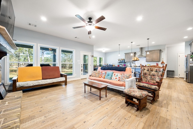 living room featuring visible vents, baseboards, ceiling fan, light wood-type flooring, and recessed lighting