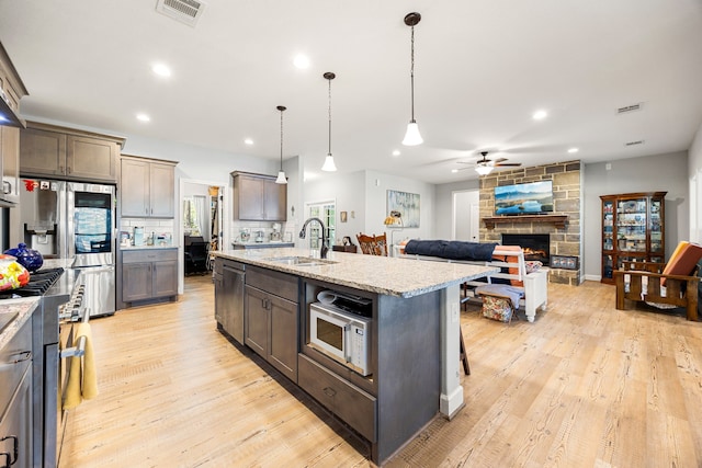 kitchen with a ceiling fan, visible vents, light wood finished floors, stainless steel appliances, and a sink