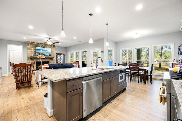 kitchen with a ceiling fan, light wood-style flooring, a fireplace, a sink, and appliances with stainless steel finishes