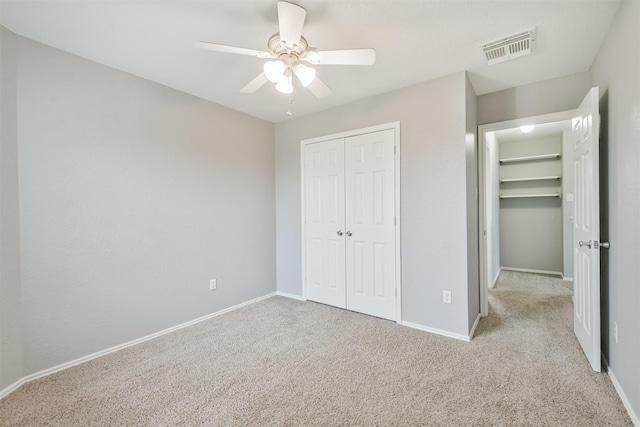 unfurnished bedroom featuring ceiling fan, light colored carpet, and a closet