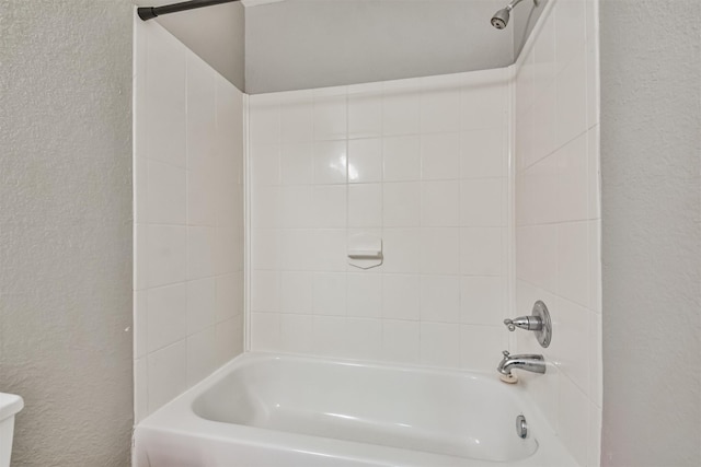 bathroom with tiled shower / bath combo and toilet