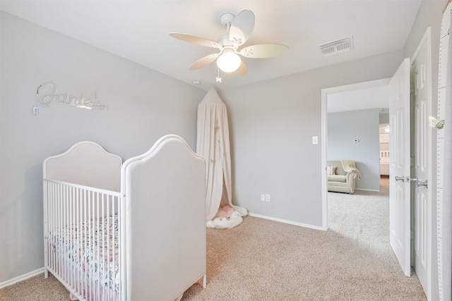 carpeted bedroom featuring ceiling fan and a nursery area