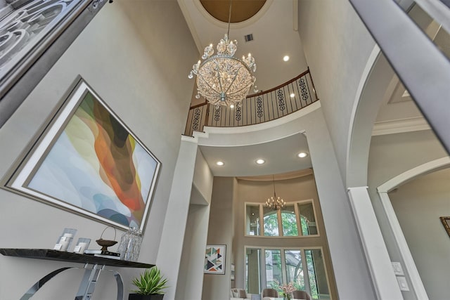 foyer entrance with a chandelier, a high ceiling, and ornamental molding