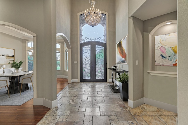 foyer featuring french doors, a towering ceiling, and a notable chandelier