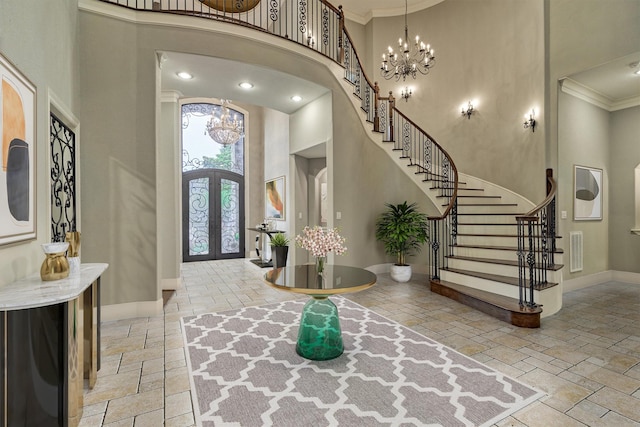 entryway featuring an inviting chandelier, crown molding, a high ceiling, and french doors