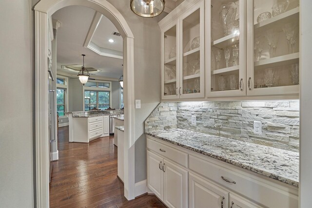 bar with decorative backsplash, dark hardwood / wood-style flooring, ornamental molding, a raised ceiling, and white cabinetry