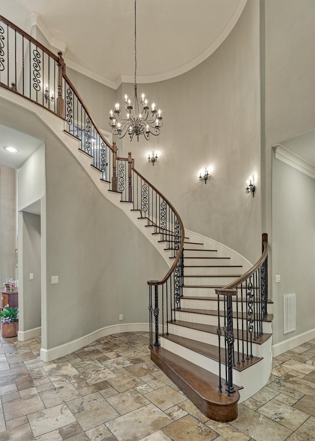 stairs with a towering ceiling, ornamental molding, and an inviting chandelier