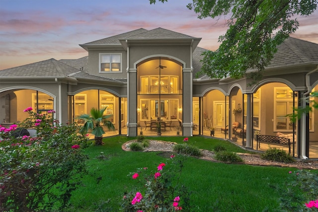 back house at dusk with a patio area and a yard