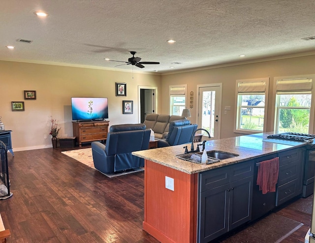 kitchen featuring ceiling fan, sink, an island with sink, and a textured ceiling