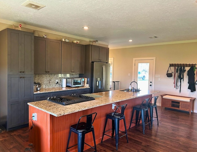 kitchen with a center island with sink, a kitchen breakfast bar, stainless steel fridge with ice dispenser, and a textured ceiling