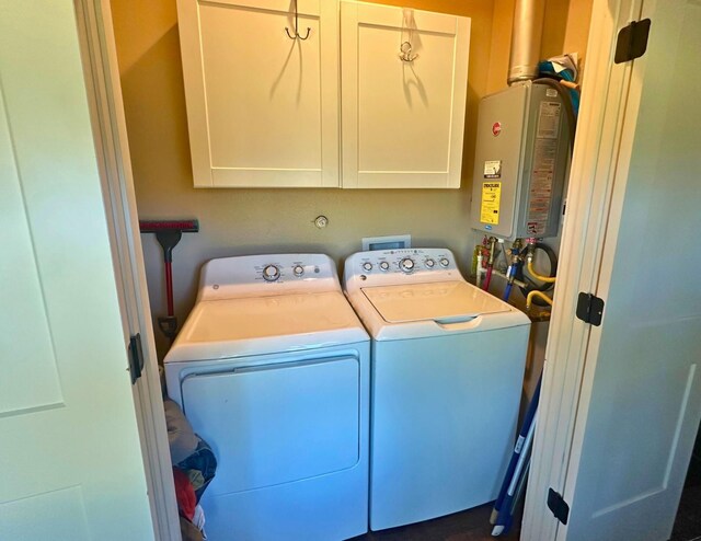 clothes washing area with washing machine and dryer, tankless water heater, and cabinets