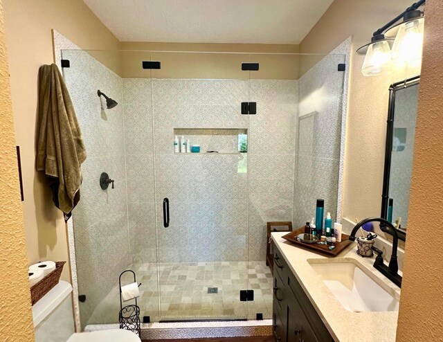 bathroom featuring vanity, toilet, and a shower with shower door