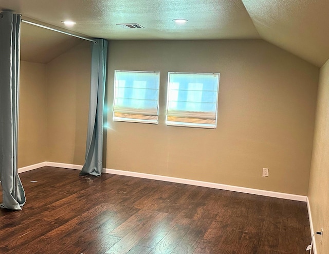 interior space featuring dark hardwood / wood-style floors, lofted ceiling, and a textured ceiling