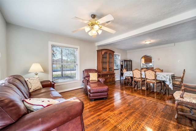 living room with a textured ceiling, ceiling fan, and dark hardwood / wood-style floors