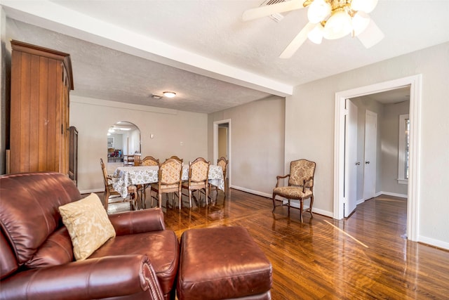 living room with beam ceiling, ceiling fan, dark hardwood / wood-style flooring, and a textured ceiling