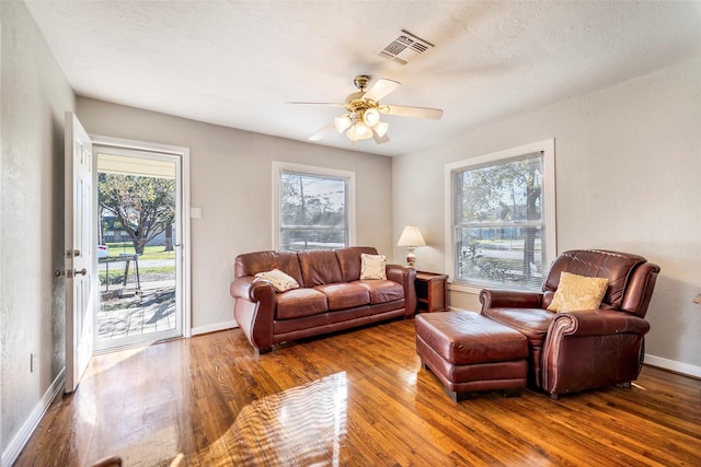 living room with ceiling fan, a healthy amount of sunlight, wood-type flooring, and a textured ceiling