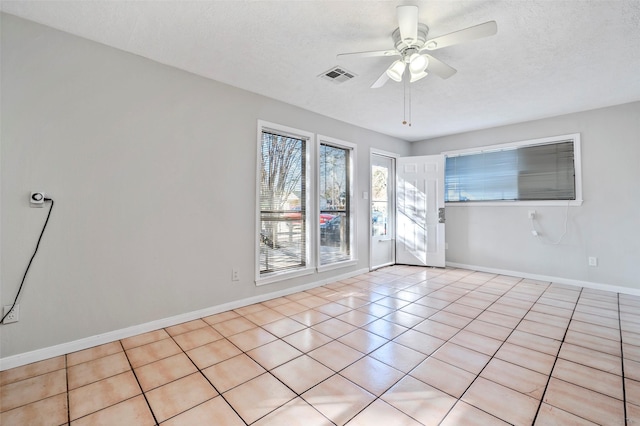 empty room with ceiling fan, light tile patterned floors, and a textured ceiling