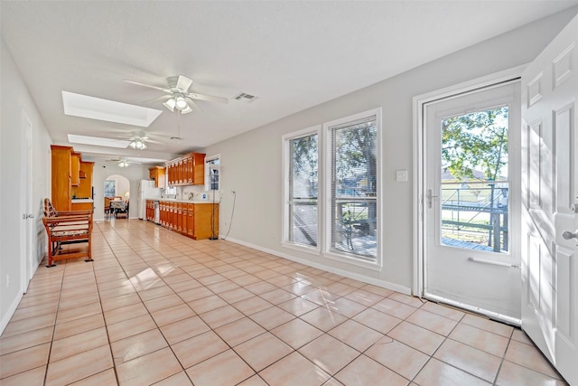 713 Firnat St, Houston, TX 77022 - kitchen featuring a ceiling fan, light tile patterned floors, brown cabinetry, light countertops, and a skylight