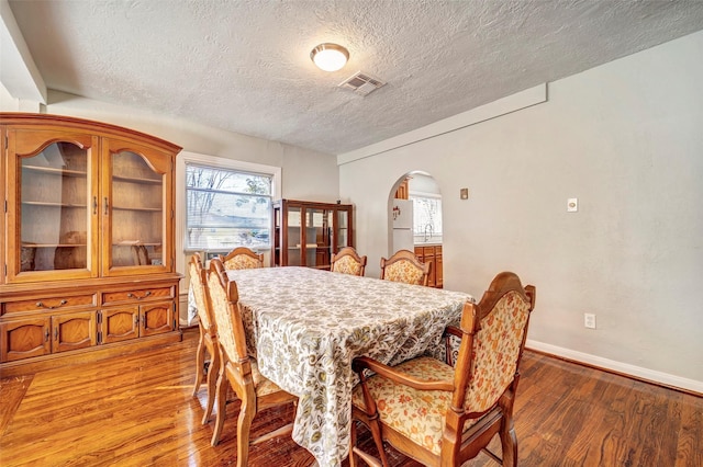 713 Firnat St, Houston, TX 77022 - dining area with a textured ceiling, wood finished floors, arched walkways, and baseboards