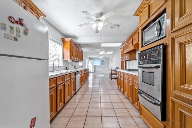 713 Firnat St, Houston, TX 77022 - kitchen featuring appliances with stainless steel finishes, a warming drawer, ceiling fan, light tile patterned flooring, and light countertops