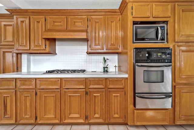 kitchen featuring decorative backsplash, appliances with stainless steel finishes, and light tile patterned flooring