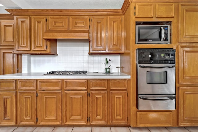 713 Firnat St, Houston, TX 77022 - kitchen with stainless steel appliances, a warming drawer, light countertops, and brown cabinetry