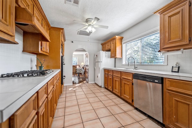 kitchen featuring ceiling fan, a textured ceiling, light tile patterned floors, custom range hood, and appliances with stainless steel finishes