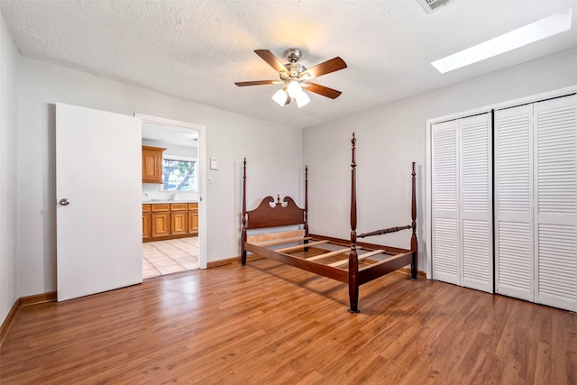 bedroom with ceiling fan, a closet, a textured ceiling, and light wood-type flooring