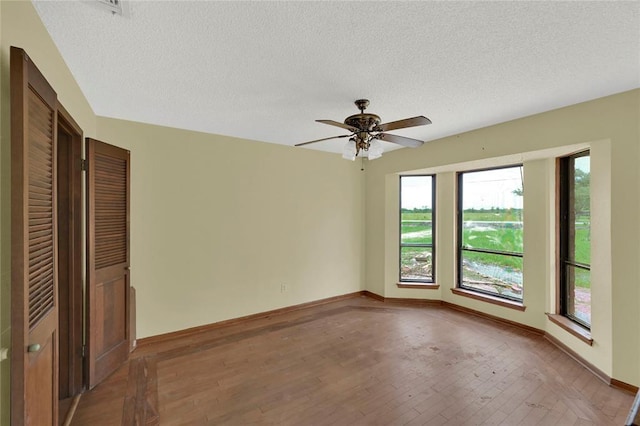 empty room with ceiling fan, a textured ceiling, and light wood-type flooring