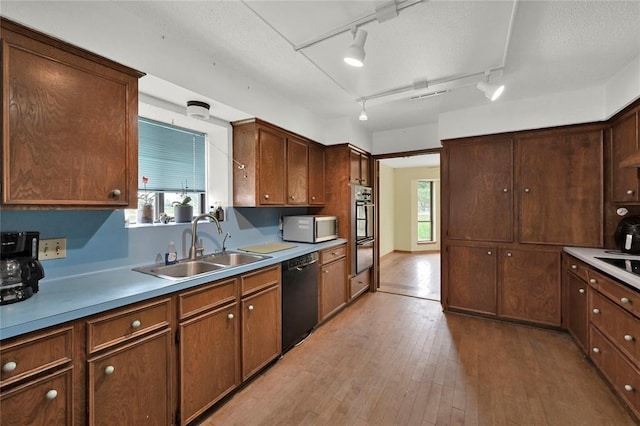 kitchen with rail lighting, dark brown cabinetry, sink, black appliances, and light hardwood / wood-style flooring