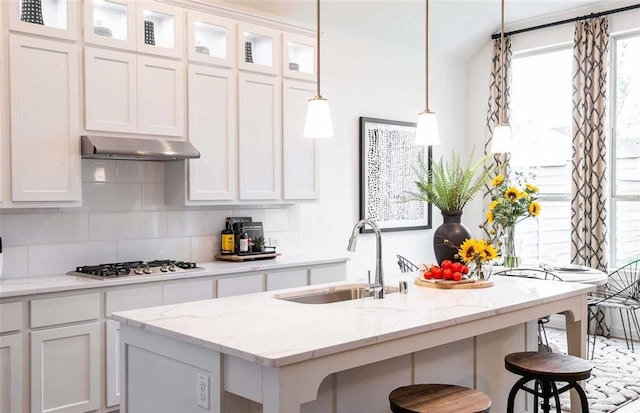 kitchen with white cabinets, a center island with sink, white gas cooktop, and exhaust hood