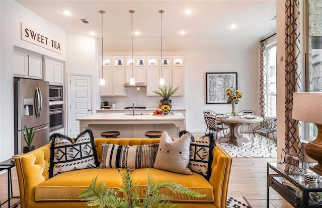 kitchen with stainless steel appliances, tasteful backsplash, a breakfast bar, white cabinets, and a center island with sink