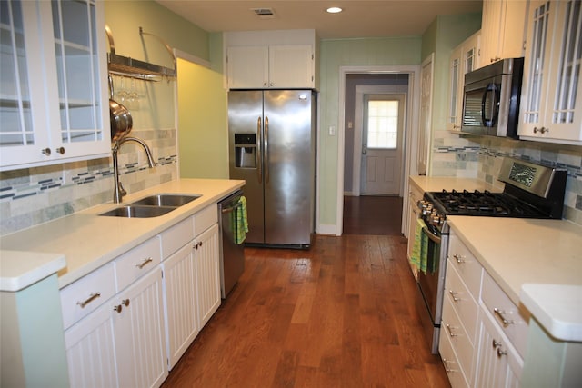 kitchen with white cabinetry, sink, dark wood-type flooring, stainless steel appliances, and tasteful backsplash