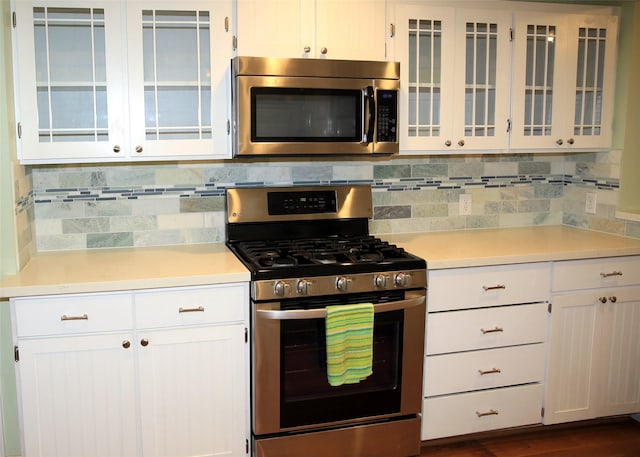 kitchen featuring stainless steel appliances, white cabinetry, and tasteful backsplash