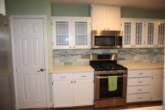 kitchen with white cabinets, appliances with stainless steel finishes, and decorative backsplash