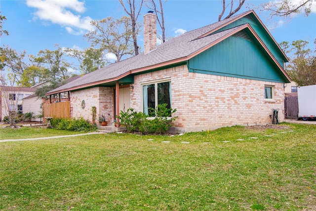 view of front of house featuring a front yard, brick siding, fence, and a chimney