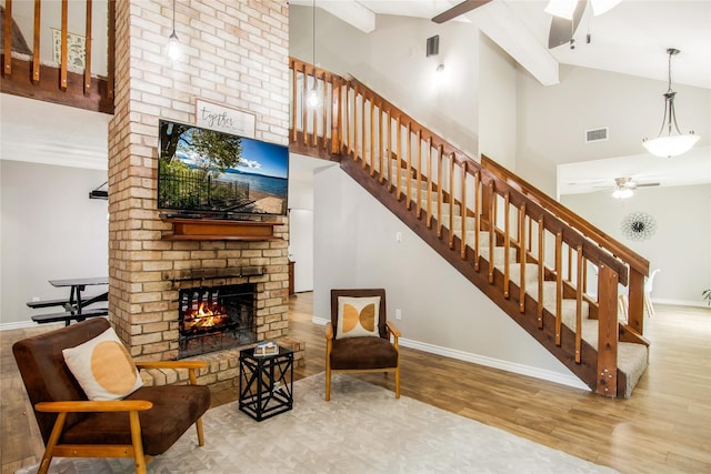 living room featuring ceiling fan, beamed ceiling, high vaulted ceiling, a fireplace, and hardwood / wood-style flooring