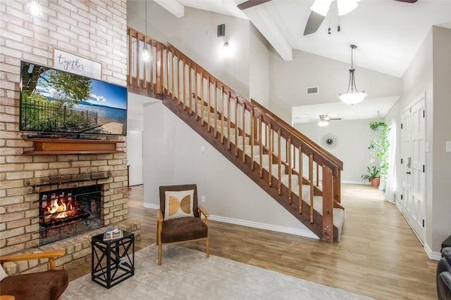 interior space featuring a brick fireplace, ceiling fan, beam ceiling, high vaulted ceiling, and hardwood / wood-style floors