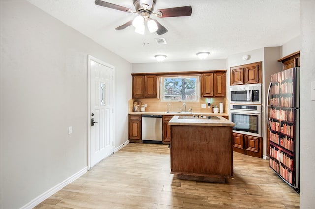 kitchen with decorative backsplash, appliances with stainless steel finishes, a center island, and light hardwood / wood-style floors